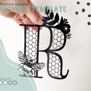 May include: Black papercut template of the letter R with a honeycomb pattern, a bee, and floral accents. The template is labeled "Papercut Template" and "Good Goose Designs".
