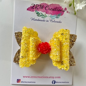 K&ouml;nnte beinhalten: Gelber und goldener Glitzerbogen mit roter Rosenverzierung. Die Schleife ist handgefertigt in Colorado und auf Etsy erh&auml;ltlich.