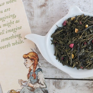May include: A white ceramic teapot with a green tea blend containing dried fruit pieces and orange peel. The tea is in a white bowl with a handle.