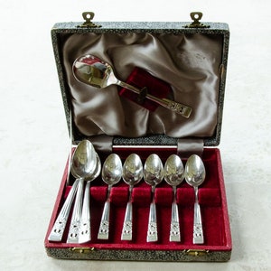 May include: A set of silver teaspoons in a velvet-lined box. The box is closed and has a silver spoon on top.