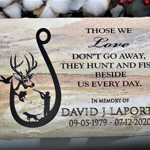 Peut inclure: Une plaque en pierre rectangulaire avec un grain naturel beige et brun. Elle pr&eacute;sente un motif noir en forme d'hame&ccedil;on contenant un cerf, un poisson, un chasseur et un chien. Le texte indique : THOSE WE Love DON'T GO AWAY, THEY HUNT AND FISH BESIDE US EVERY DAY. IN MEMORY OF DAVID J LAPORTE 09-05-1979 - 07-12-2020.