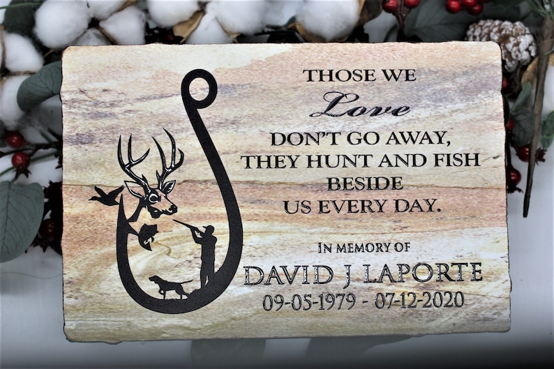 Peut inclure: Une plaque en pierre rectangulaire avec un grain naturel beige et brun. Elle pr&eacute;sente un motif noir en forme d'hame&ccedil;on contenant un cerf, un poisson, un chasseur et un chien. Le texte indique : THOSE WE Love DON'T GO AWAY, THEY HUNT AND FISH BESIDE US EVERY DAY. IN MEMORY OF DAVID J LAPORTE 09-05-1979 - 07-12-2020.