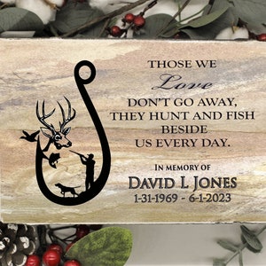Peut inclure: Une plaque en pierre rectangulaire avec une finition naturelle beige et grise. Elle pr&eacute;sente un graphique noir en forme d'hame&ccedil;on avec un cerf, un poisson, un chasseur et un chien. Le texte indique : THOSE WE Love DON'T GO AWAY, THEY HUNT AND FISH BESIDE US EVERY DAY. IN MEMORY OF DAVID L JONES 31-01-1969 - 01-06-2023.