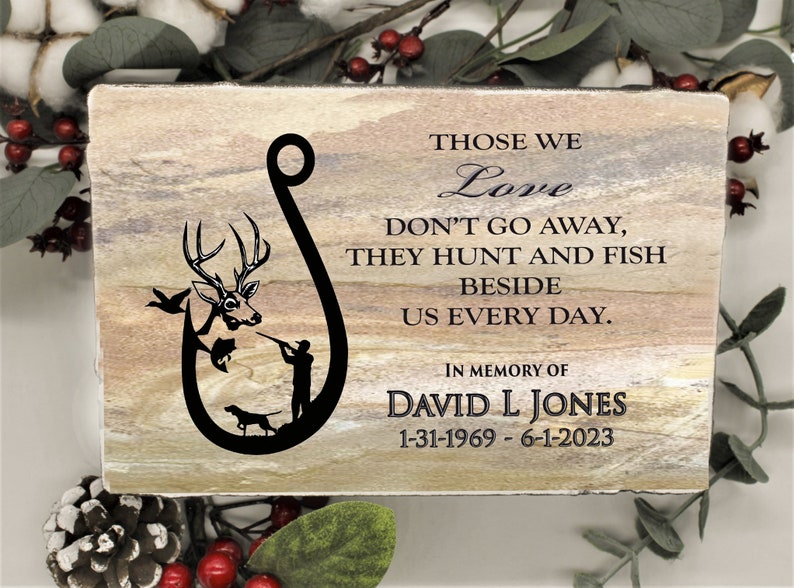 Peut inclure: Une plaque en pierre rectangulaire avec une finition naturelle beige et grise. Elle pr&eacute;sente un graphique noir en forme d'hame&ccedil;on avec un cerf, un poisson, un chasseur et un chien. Le texte indique : THOSE WE Love DON'T GO AWAY, THEY HUNT AND FISH BESIDE US EVERY DAY. IN MEMORY OF DAVID L JONES 31-01-1969 - 01-06-2023.