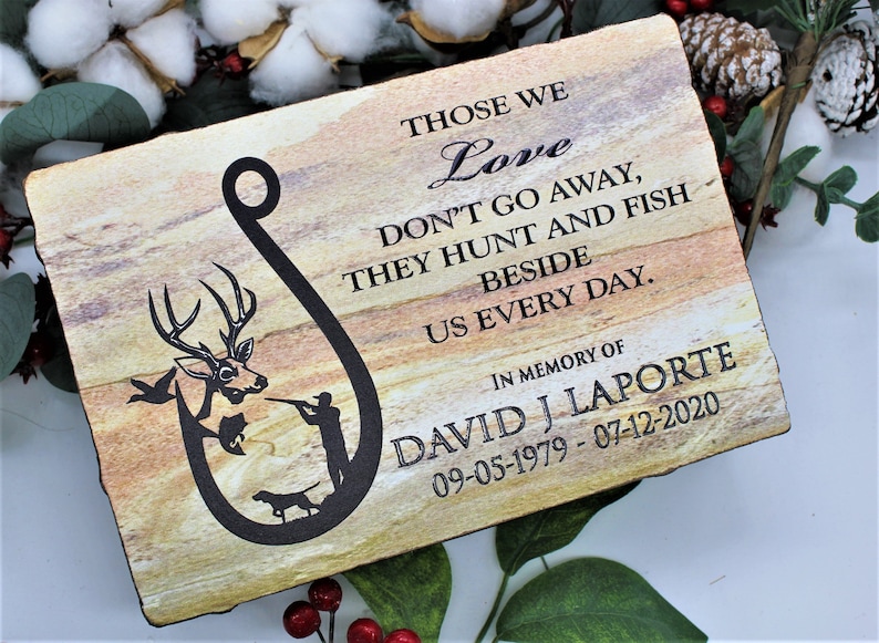 Peut inclure: Une plaque rectangulaire en pierre avec une texture naturelle en couches beige et marron. Elle pr&eacute;sente un motif noir en forme d'hame&ccedil;on contenant un cerf, un chasseur et un chien. Le texte indique : THOSE WE Love DON'T GO AWAY, THEY HUNT AND FISH BESIDE US EVERY DAY. IN MEMORY OF DAVID J LAPORTE 09-05-1979 - 07-12-2020.