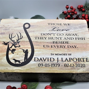 Peut inclure: Une plaque comm&eacute;morative rectangulaire en pierre avec une texture stratifi&eacute;e beige et brune. Elle pr&eacute;sente un motif grav&eacute; noir en forme d'hame&ccedil;on avec un cerf, un poisson, un chasseur et un chien. Le texte indique : THOSE WE Love DON'T GO AWAY, THEY HUNT AND FISH BESIDE US EVERY DAY. IN MEMORY OF DAVID J LAPORTE 09-05-1979 - 07-12-2020.