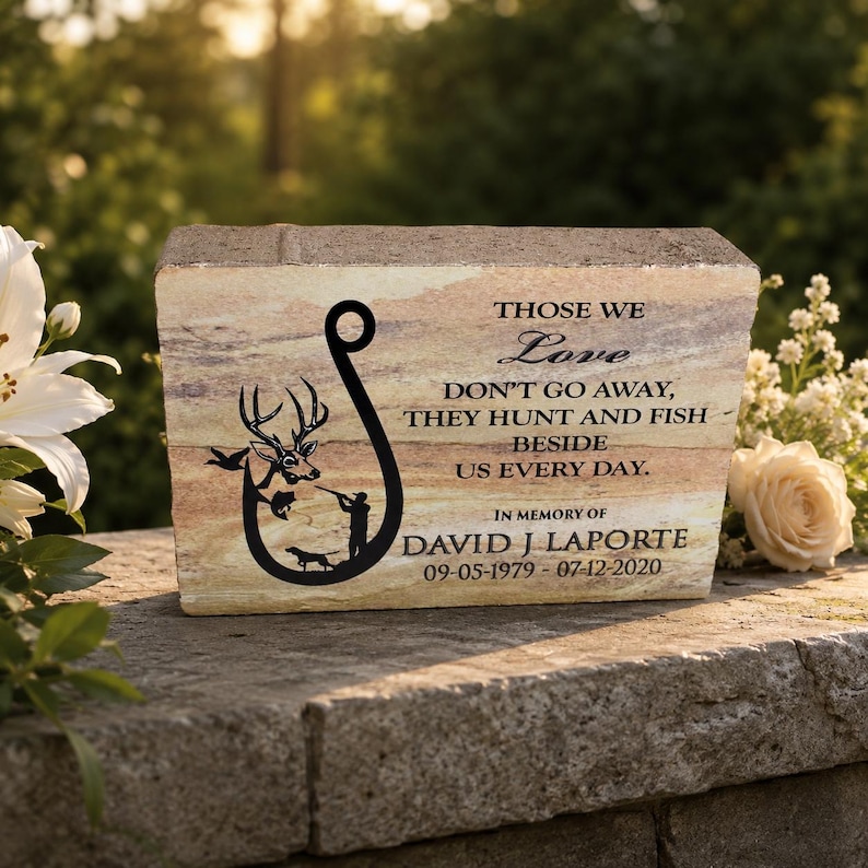 Peut inclure: Une plaque comm&eacute;morative rectangulaire en pierre avec une texture marbr&eacute;e beige et brune. Elle pr&eacute;sente un graphique noir repr&eacute;sentant un hame&ccedil;on, un cerf, un chasseur et un chien. Le texte indique : THOSE WE Love DON'T GO AWAY, THEY HUNT AND FISH BESIDE US EVERY DAY. IN MEMORY OF DAVID J LAPORTE 09-05-1979 - 07-12-2020.