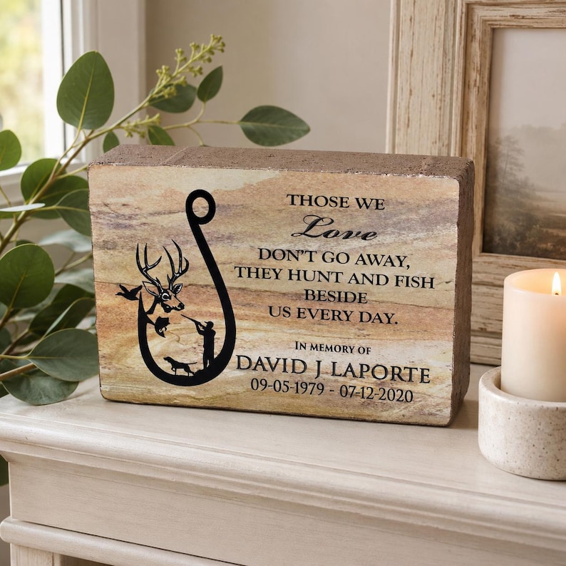 Peut inclure: Une plaque comm&eacute;morative rectangulaire en pierre avec un graphique noir repr&eacute;sentant un hame&ccedil;on, un cerf, un chasseur et un chien. Le texte indique : THOSE WE Love DON'T GO AWAY, THEY HUNT AND FISH BESIDE US EVERY DAY. IN MEMORY OF DAVID J LAPORTE 09-05-1979 - 07-12-2020.