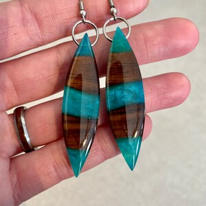 May include: Teal and brown wood resin earrings with silver hooks.