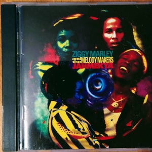 May include: CD cover featuring a colorful, abstract design with four people's faces. The text reads "Ziggy Marley and the Melody Makers Jahmekyah".