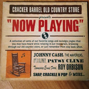 May include: A vintage-style poster advertising a collection of country music songs. The poster features a rocking chair, a record player, and the text "Cracker Barrel Old Country Store presents "Now Playing"". The poster lists artists including Johnny Cash, Patsy Cline, and Roy Orbison.