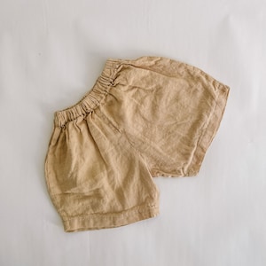May include: A pair of beige linen shorts with an elastic waistband.