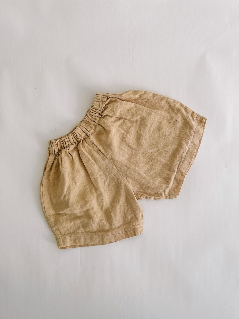 May include: A pair of beige linen shorts with an elastic waistband.