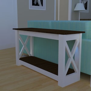 Peut inclure: Console blanche avec un plateau brun et une étagère inférieure. La table a un design en forme de X sur les pieds avant. La table est dans un salon.