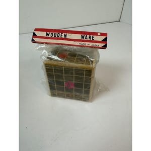 May include: A wooden box with a grid pattern, packaged in clear plastic. The box is topped with a red, white, and blue label that reads "WOODEN WARE MADE IN JAPAN."