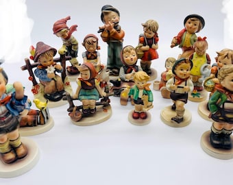 Könnte beinhalten: Eine Sammlung von 15 handbemalten Porzellanfiguren von Kindern in traditioneller deutscher Kleidung. Die Figuren sind alle unterschiedlich groß und weisen verschiedene Details auf, wie Hüte, Körbe und Musikinstrumente.