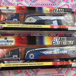 May include: Two limited edition Kenworth tractor-trailer models in their original packaging. One features the Edmonton Oilers logo, the other the Vancouver Canucks logo. Both are 1:80 scale and from Fleer Collectibles.