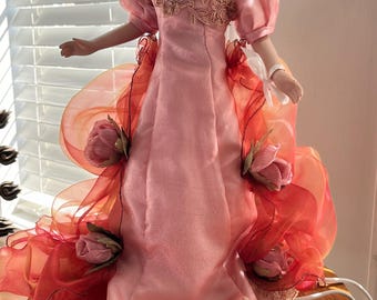 Vintage  porcelain doll table lamp featuring an illuminated orange-glowing skirt beneath a pink and red ruffled gown.