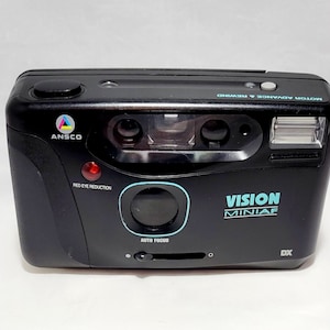 May include: A black Ansco Vision Miniaf 35mm film camera with a built-in flash and auto focus. The camera has a red eye reduction feature and a DX film type indicator.