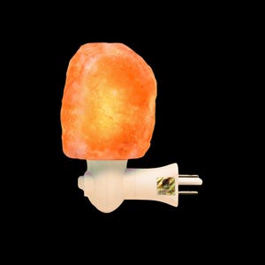 May include: A Himalayan salt lamp night light. The lamp features a large, orange, textured salt crystal atop a white plug-in base. It is designed to plug directly into a wall socket. The background is black.