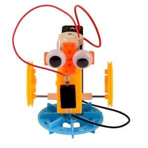 Op de afbeelding: Een speelgoedrobot met oranje en gele kunststof onderdelen, zwarte ogen en rode en zwarte draden. De robot heeft twee blauwe wielen en een batterijvak.