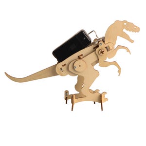 May include: A wooden, light brown dinosaur model with articulated joints and a black battery pack attached to its back. The dinosaur has a detailed head and is standing on a small wooden base. The model is designed for assembly.