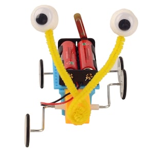 Può includere: Un robot giocattolo blu e giallo con occhietti e due batterie rosse. Il robot ha quattro ruote ed è fatto di plastica e metallo.