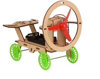 May include: A wooden toy car with a red propeller and green wheels. The car has a battery compartment and a small seat. The propeller is attached to a circular frame.
