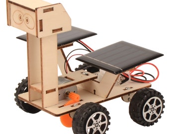 May include: A wooden toy car with a solar panel on top and a tall, rectangular head. The car has four black wheels and a small orange gear visible on the side. The car is powered by the sun.