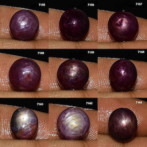 以下が含まれることがあります： 9つの研磨された丸い深紅色の宝石。各宝石は、表面に星のような模様を表示します。宝石はニュートラルな背景に対して表示され、色とユニークな内部構造を強調しています。宝石の色と模様はわずかに異なります。