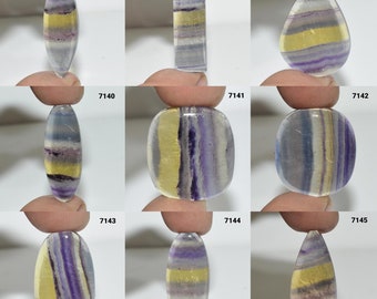 May include: Nine different fluorite cabochons in various shapes and sizes. The cabochons are all a mix of purple, yellow, and white.