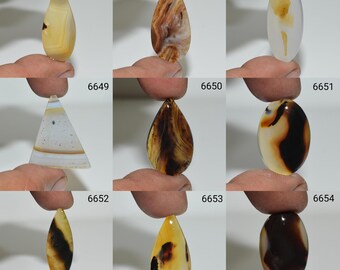 May include: Assortment of 10 agate cabochons in various shapes and colors, including brown, black, white, and yellow. The cabochons are displayed on a hand.
