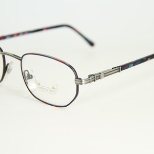 以下が含まれることがあります： シルバーのメタルフレームと柄入りのテンプルが付いた、楕円形の眼鏡。縁は濃い赤色で縁取られています。テンプルにはカラフルな花柄が施されています。レンズは透明です。