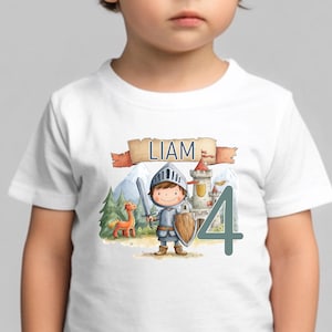 Könnte beinhalten: Weißes T-Shirt mit einer Aquarellillustration eines Ritters, einer Burg und eines Pferdes. Das Design enthält den Namen "LIAM" auf einem Banner und die Zahl "4". Der Ritter hält ein Schwert und einen Schild.