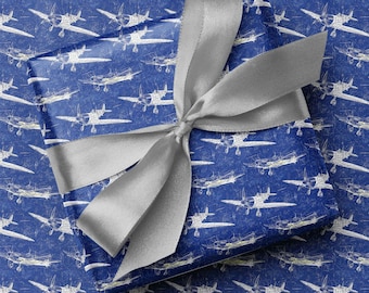 May include: A wrapped gift with blue paper featuring a white airplane pattern. The gift is tied with a silver satin ribbon, forming a large bow on top. The overall presentation is neat and festive.