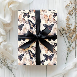 May include: A gift box wrapped in white paper with a black ribbon and a pattern of brown and black butterflies.