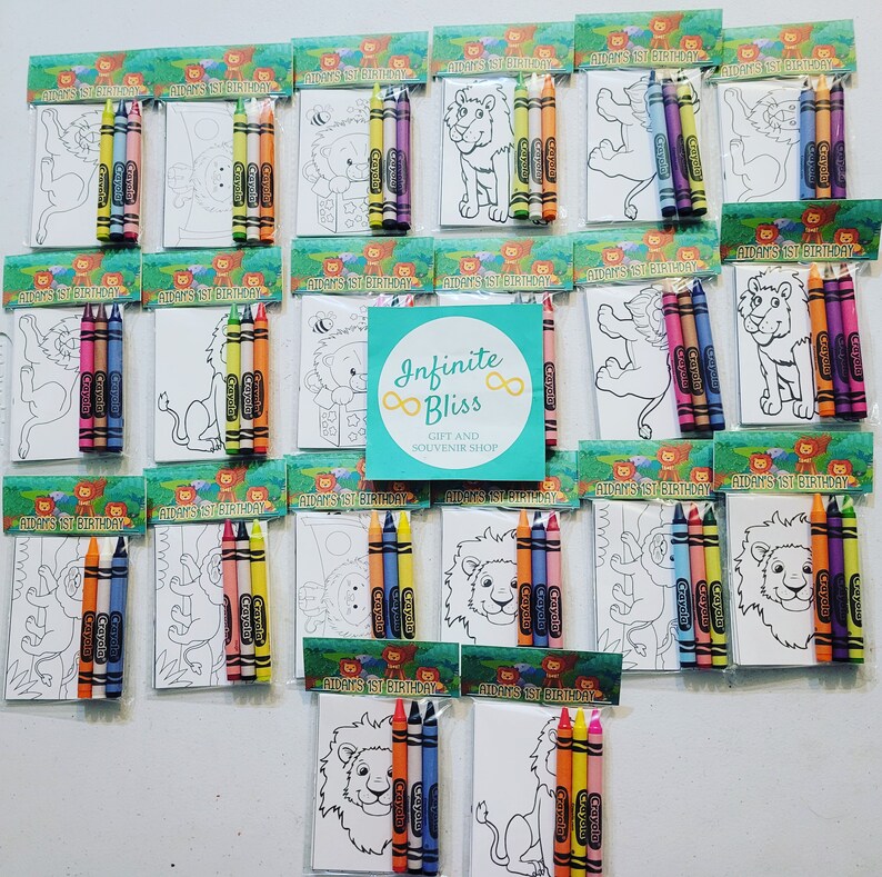 K&ouml;nnte beinhalten: Ein Set mit 18 Malvorlagen mit einem L&ouml;wenmotiv. Jede Seite ist mit vier Buntstiften in einem durchsichtigen Plastikbeutel verpackt. Die Beutel sind mit dem Text "Aidan's 1st Birthday" beschriftet. Der Text "Infinite Bliss Gift and Souvenir Shop" ist auf einem t&uuml;rkisfarbenen Hintergrund gedruckt.