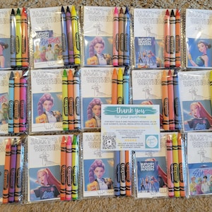 K&ouml;nnte beinhalten: Mehrere Buntstiftpackungen und Malb&uuml;cher sind auf einer Oberfl&auml;che angeordnet. Jede Packung enth&auml;lt ein Set Buntstifte und ein Malbuch mit dem Text "JAZZY'S BIRTHDAY". Einige Malb&uuml;cher zeigen Bilder von animierten Charakteren.