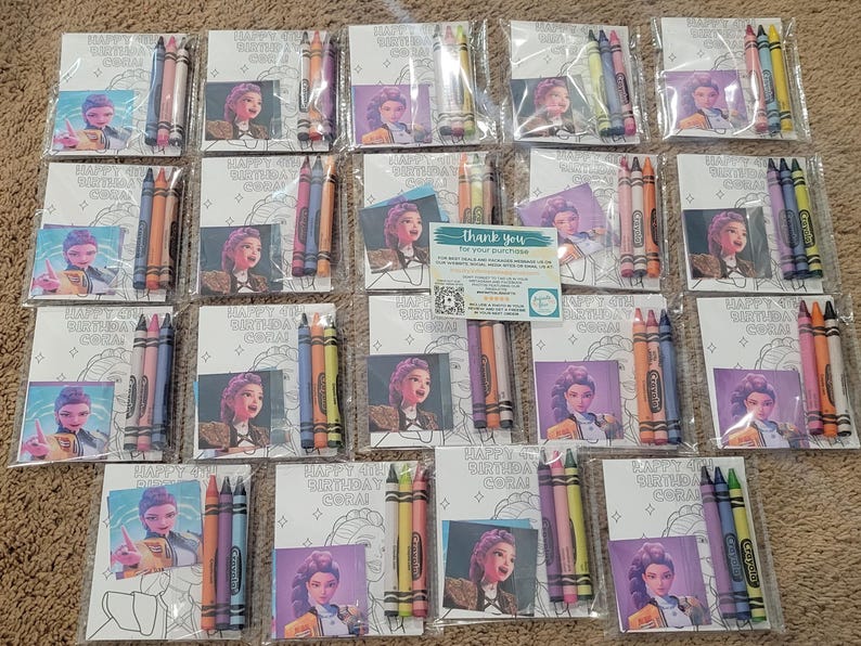 K&ouml;nnte beinhalten: Eine Sammlung von Buntstift-Sets, jeweils in durchsichtigem Kunststoff verpackt. Jedes Set enth&auml;lt eine Malvorlage mit einem Cartoon-Bild und dem Text "HAPPY 4TH BIRTHDAY CORAL". Die Sets sind auf einer braunen Oberfl&auml;che angeordnet.