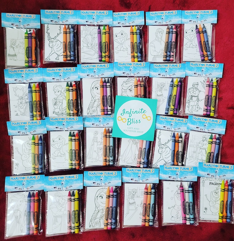 May include: A set of 20 Frozen-themed coloring pages and crayons packaged in clear plastic bags. Each bag has a blue and white label with the text "HARLYNN TURNS 2". The bags are arranged in rows on a red surface. The coloring pages feature characters from the movie Frozen, such as Elsa, Anna, Olaf, and Kristoff. The crayons are Crayola brand and come in a variety of colors.