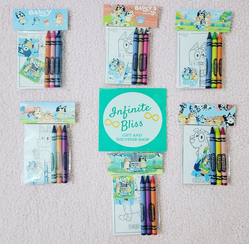 May include: A set of six Bluey-themed coloring packs, each containing a coloring page, stickers, and four crayons. The packs feature different characters from the show, including Bluey, Bingo, and Bandit. The crayons are Crayola brand and are in the colors blue, green, orange, and purple. The packs are packaged in clear plastic bags with a header card that says "Bluey's Shop". The header card also features a logo with the words "Infinite Bliss" and "Gift and Souvenir Shop".