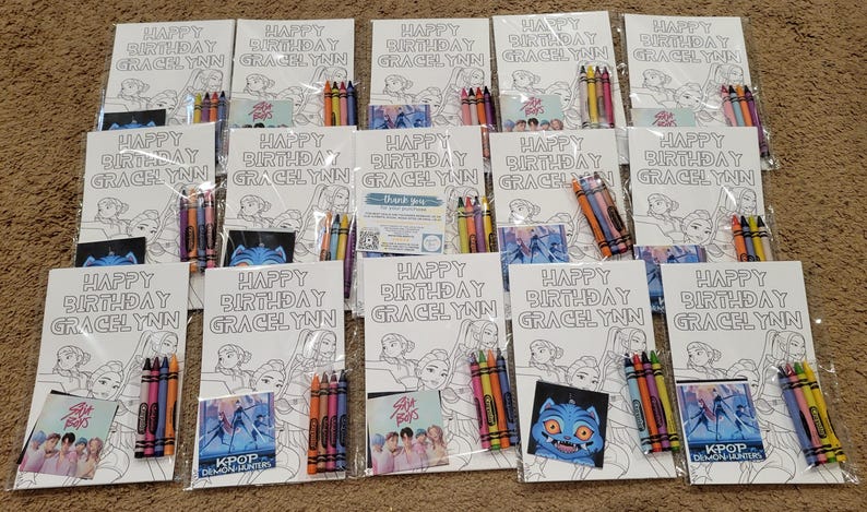 K&ouml;nnte beinhalten: Eine Sammlung von Geburtstagsgeschenken, die jeweils ein Malbuch mit dem Text "Happy Birthday Gracelynn", eine Packung Buntstifte und eine kleine Karte mit KPOP-Motiv enthalten. Die Geschenke sind in durchsichtigem Kunststoff verpackt.