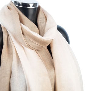 May include: A beige and white ombre scarf draped over a mannequin. The scarf is made of a soft, lightweight fabric.