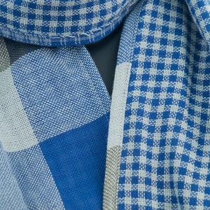 May include: A blue and white checkered fabric with a woven texture. The fabric is folded in half and the checkered pattern is visible on both sides.