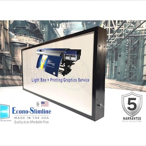 May include: A rectangular light box with a black frame displays a blue and white printer. Text on the light box reads "Light Box + Printing/Graphics Service." The light box also features the text "Econo-Slimline MADE IN THE USA Quality at an Affordable Price."