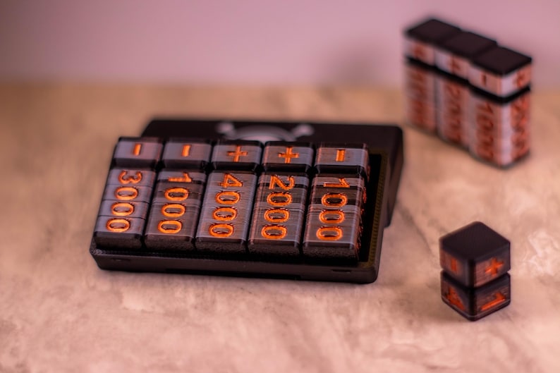 May include: A black calculator with orange illuminated numbers and symbols. The calculator has a series of buttons with numbers like 3000, 1000, 4000, 2000, and 1000. There are additional stacks of the same buttons and two dice.