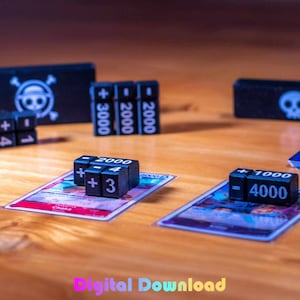 May include: A collection of black dice with white numbers and symbols, used for a card game. The dice are placed on colorful cards with Japanese text. Also included are black boxes with skull and crossbones and skull designs.