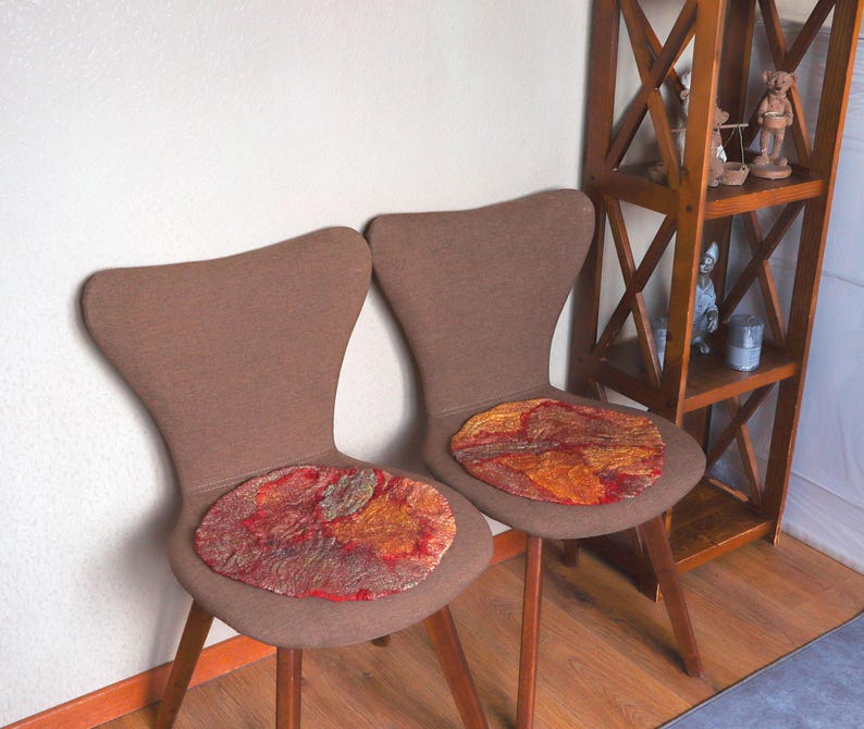 May include: Two brown chairs with wooden legs and red, orange, and gold patterned seat cushions.