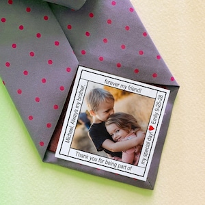 May include: A grey tie with pink polka dots has a folded card attached to it. The card has a photo of two children hugging and the text "Michael, Always my brother, Thank you for being part of my special day! Emily 9-25-28 forever my friend!"