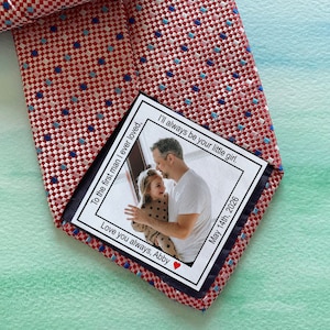 May include: A red and white patterned tie with a small card attached. The card has a photo of a man and a child, and the text "To the first man I ever loved, Love you always, Abby I'll always be your little girl. May 14th, 2026".